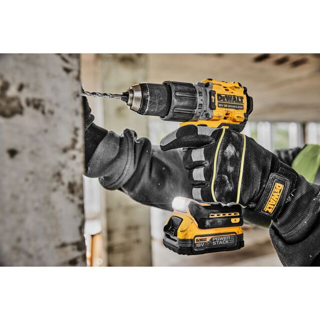 Person använder en gul och svart borrmaskin från märket Dewalt för att borra i en betongvägg.