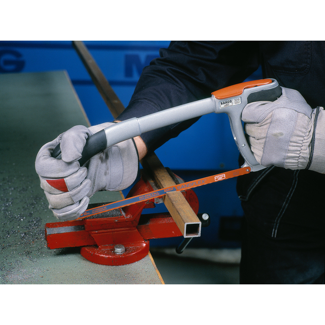 Person i handskar sågar ett metallrör med bågfil.