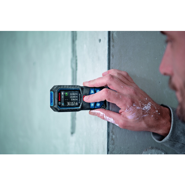 En person använder en digital laseravståndsmätare mot en betongvägg. Skärmen visar mätvärden i meter.