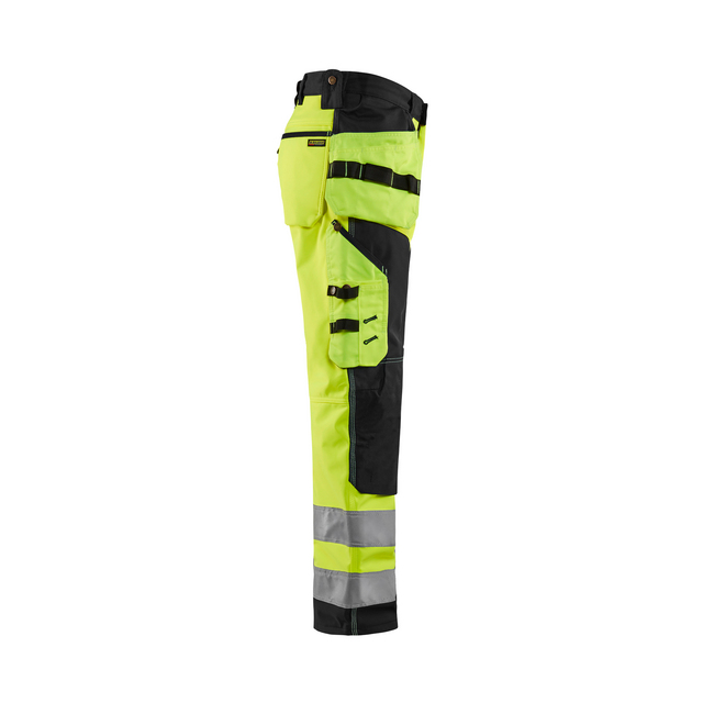 Gul och svart high visibility byxa med reflexband och flera fickor, sedd från sidan.