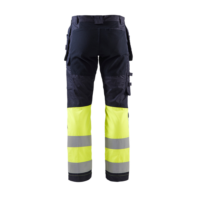 Arbetsbyxor med reflexband, gul nedre del, flera fickor, sedd bakifrån.