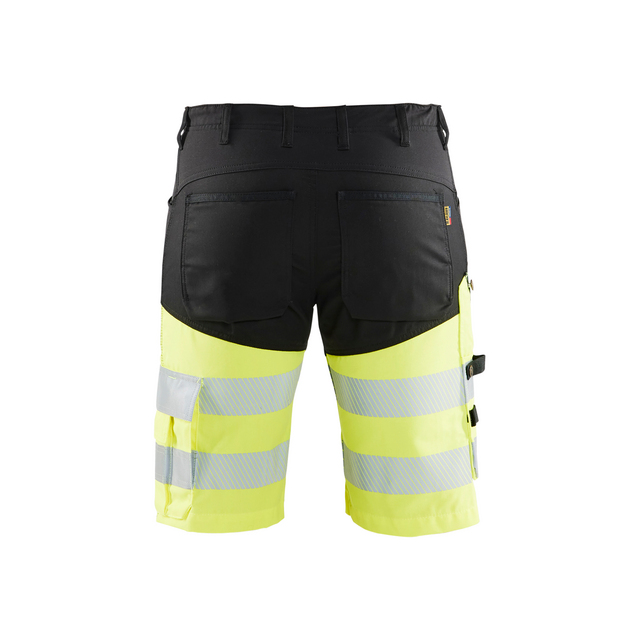 Shorts i svart och neongult med reflexband och flera fickor, sedda bakifrån.