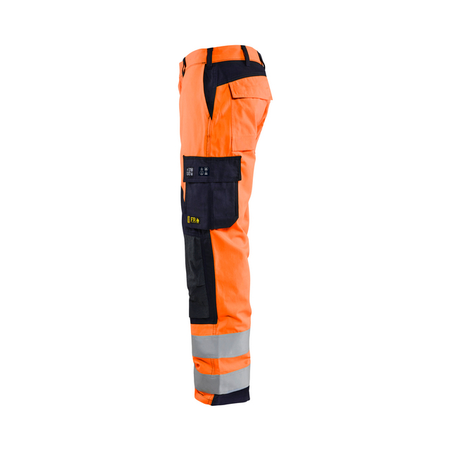 Orange arbetsbyxor med svarta och reflekterande detaljer, samt fickor och hällor, visas i profil från sidan.