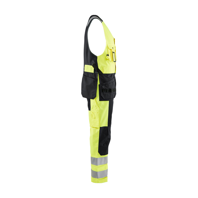 Reflexgula och svarta arbetsbyxor med hängslen och reflexband på benen, sedd från sidan.