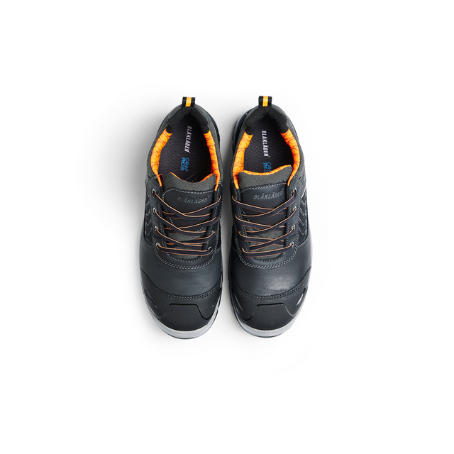 Svarta sneakers med orange foder och bruna skosnören, sedd uppifrån.