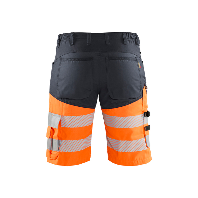 Arbetsbyxor i svart och orange med reflexband på benen och flera fickor, sett bakifrån.