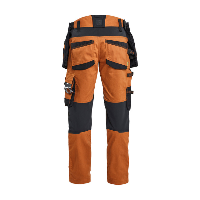Arbetsbyxor i orange och svart med flera fickor och fästen, sett bakifrån.