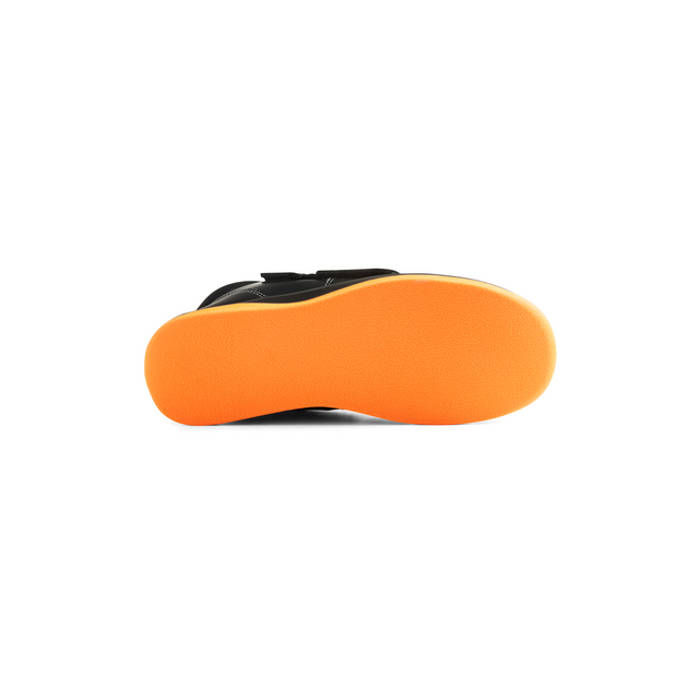 Svart sko sedd underifrån med orange sula.