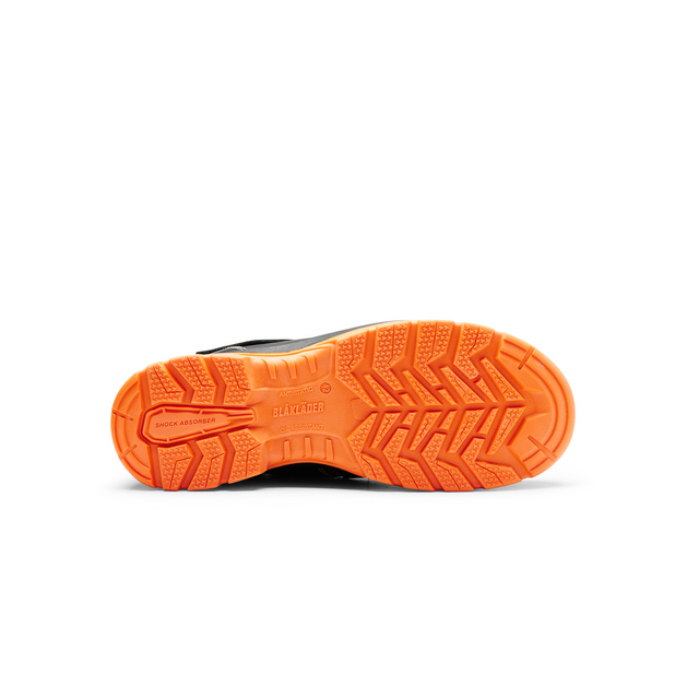 Svart och orange sula av en sko med mönster för bra grepp. Text på sulan: BLAKLADER och GRIP CONTROL.