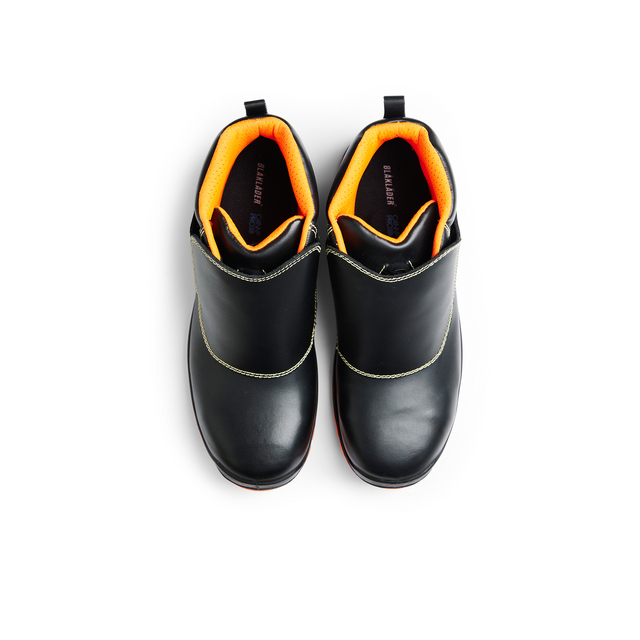 Svarta boots med orange foder och dragöglor, fotograferade ovanifrån.