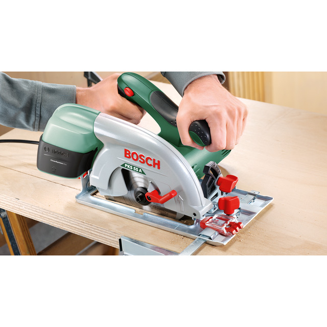 En person använder en Bosch PKS 55 A cirkelsåg för att såga en träplanka.
