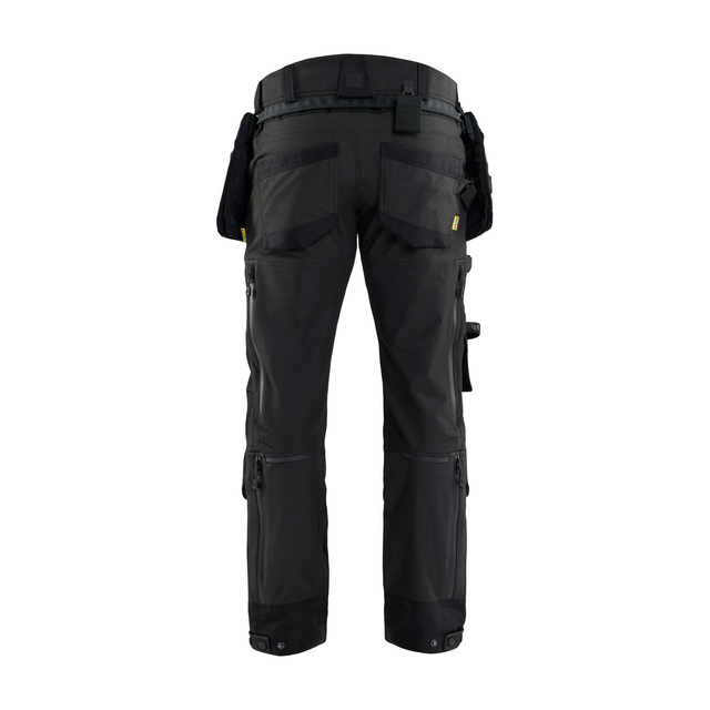 Svarta arbetsbyxor med flera fickor och hällor för verktyg i midjan, sett bakifrån.