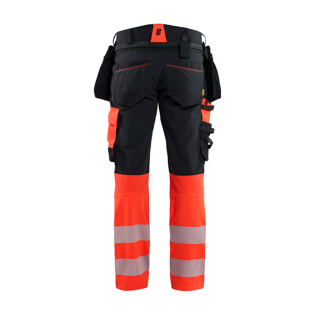 Svart och orange arbetsbyxa med reflexband och flera fickor, sedd bakifrån.