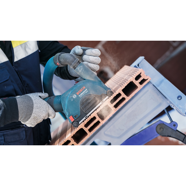 En person i skyddskläder använder en Bosch elektrisk verktyg för att bearbeta tegelblock.