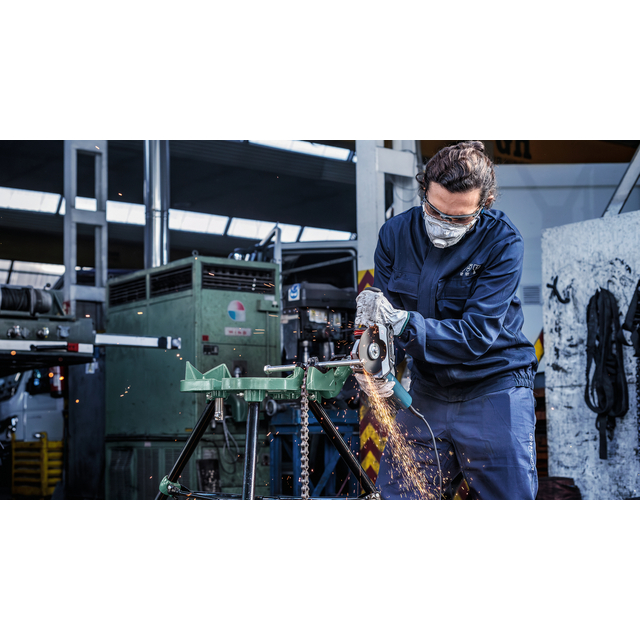 Person med ansiktsmask och skyddsglasögon använder en slipmaskin på metall, med gnistor som flyger.