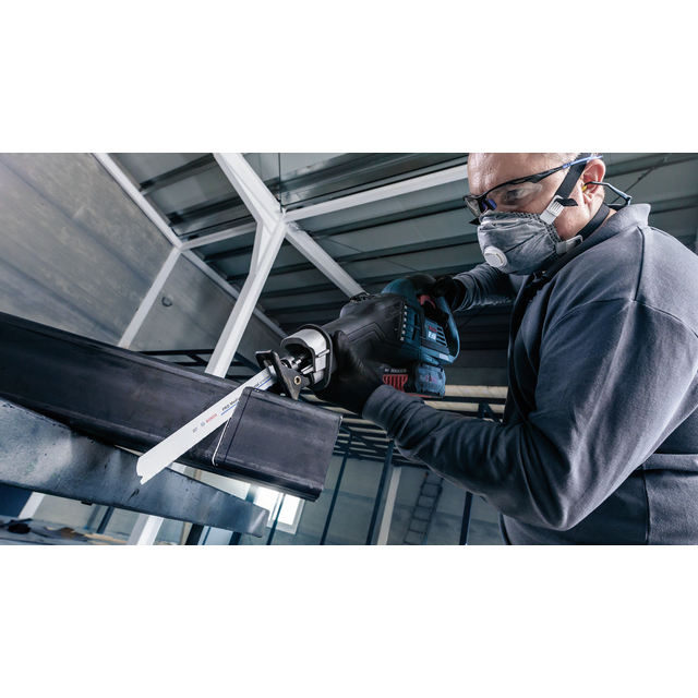 Person med skyddsglasögon och mask använder en elektrisk tigersåg för att skära genom en metallbalk.