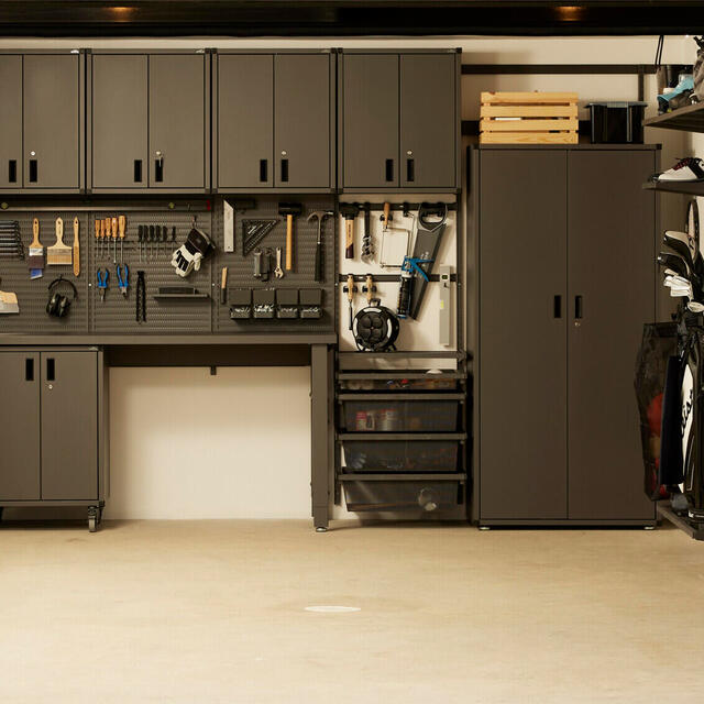 Svart garageförvaring med verktygstavla, skåp och hyllor. Verktyg och tillbehör organiserade på väggen.