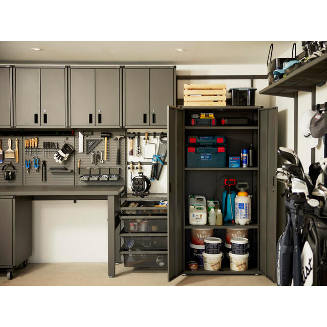 Garage med gråa förvaringsskåp, verktygstavla, förvaringslådor och hyllor med färgburkar och rengöringsprodukter.