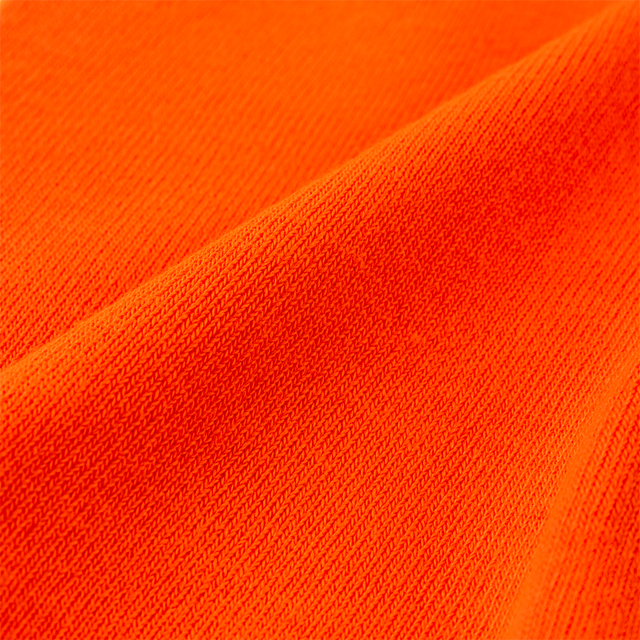 Orange tyg med stickad struktur i närbild.