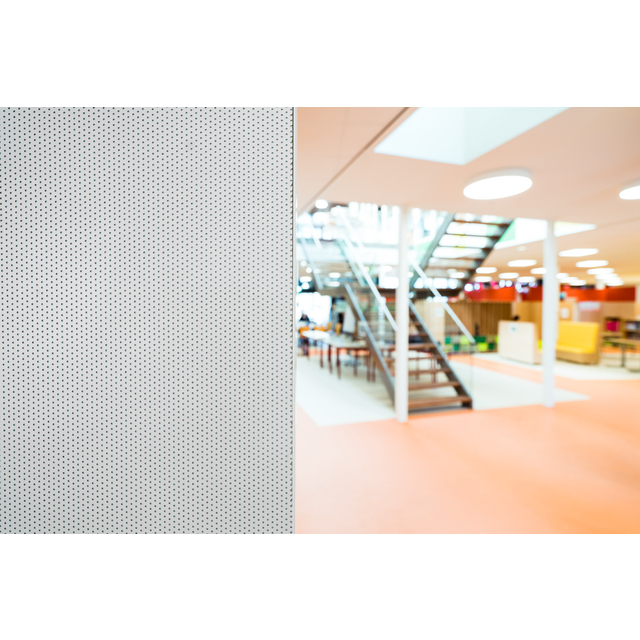 Perforerad väggpanel till vänster, modern inomhusmiljö med trappa, glasräcke och takhöga fönster i bakgrunden.